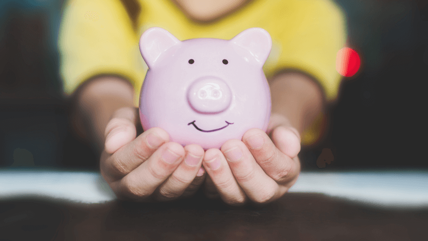 Closeup of a young child's hands holding a piggy bank