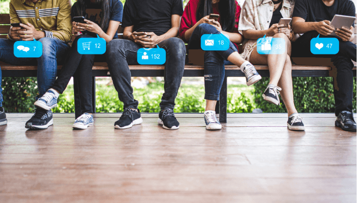Five millenials seated on a bench using their smartphones