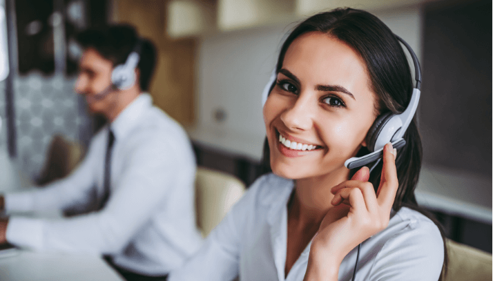 Young smiling woman with dark hair wearing a headset in a call center