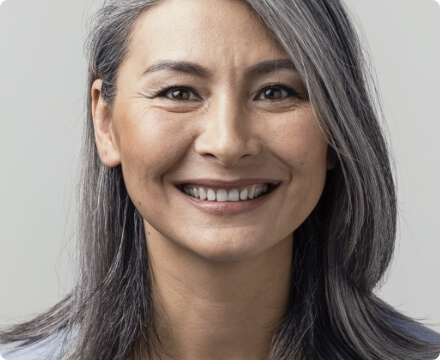 Smiling late-middle-age female against a grey background