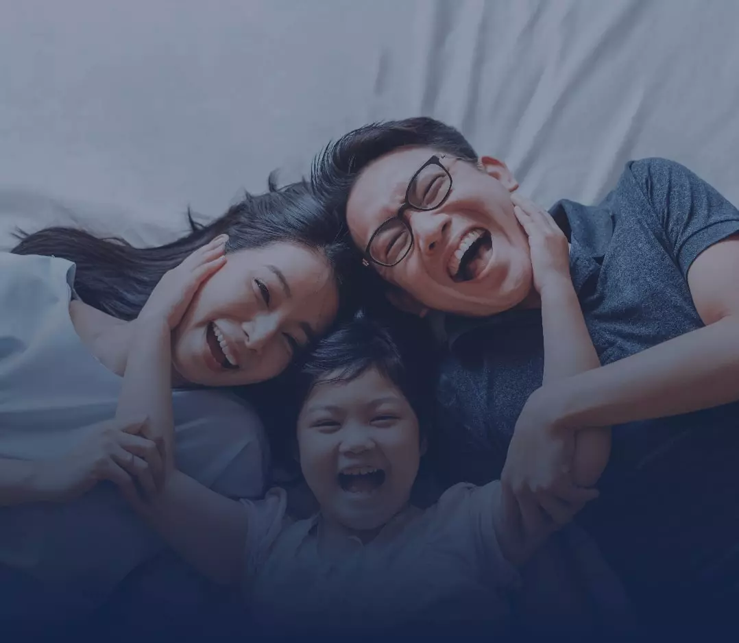 Smiling asian mother, father and child laying on a bed