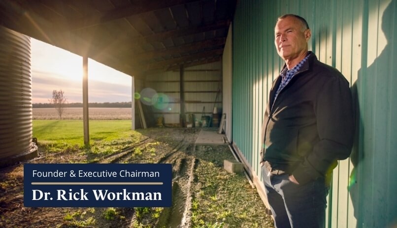 Heartland Dental Founder Dr. Rick Workman standing in a barn under a bright and beautiful sunrise