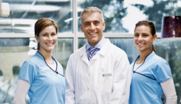 A dentist, hygienist and a dental assistant standing together