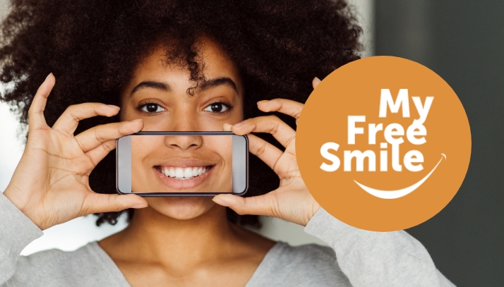 Female holding phone that is displaying a smile over mouth with my free smile logo