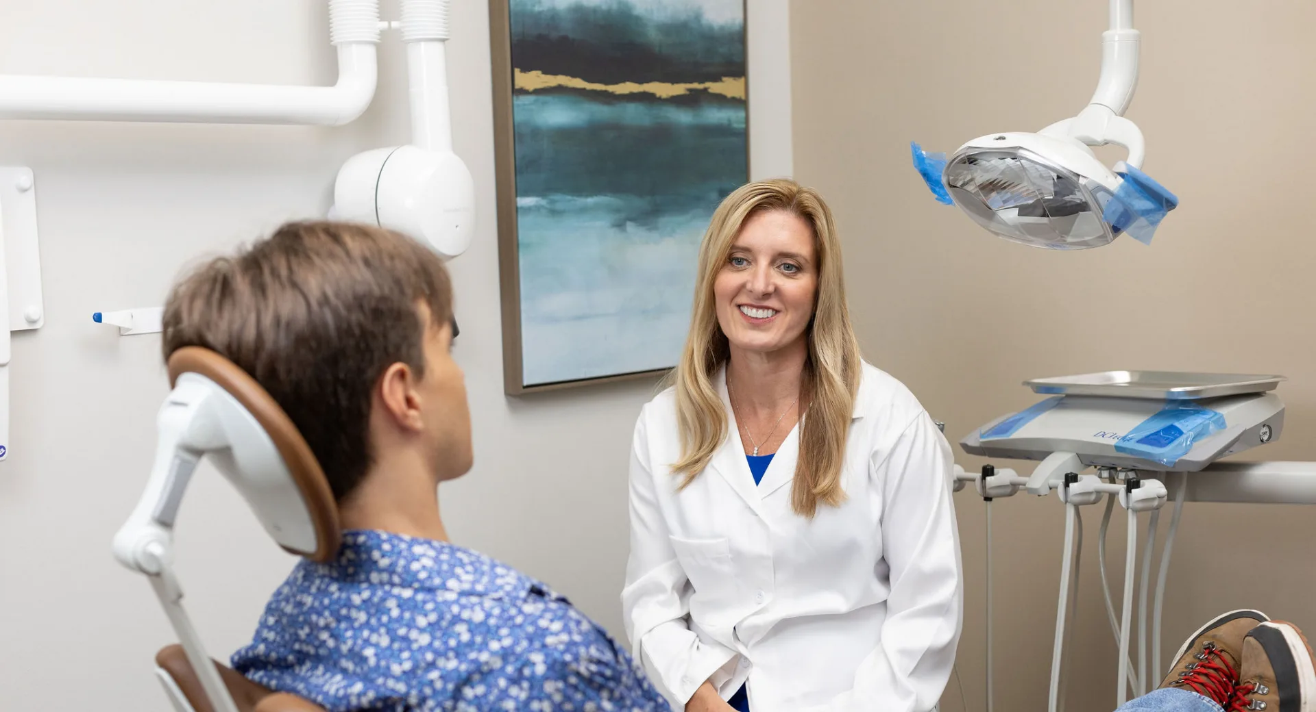 A person in a white coat talking to a person in a chair