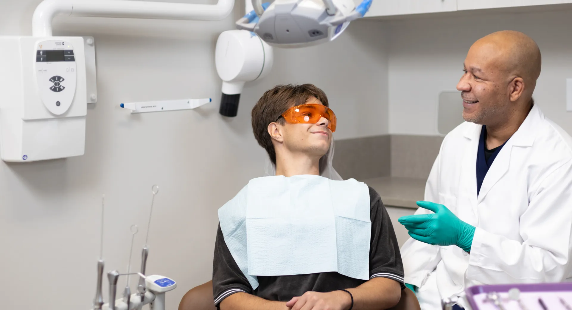 A person in a dentist's chair talking to a dentist